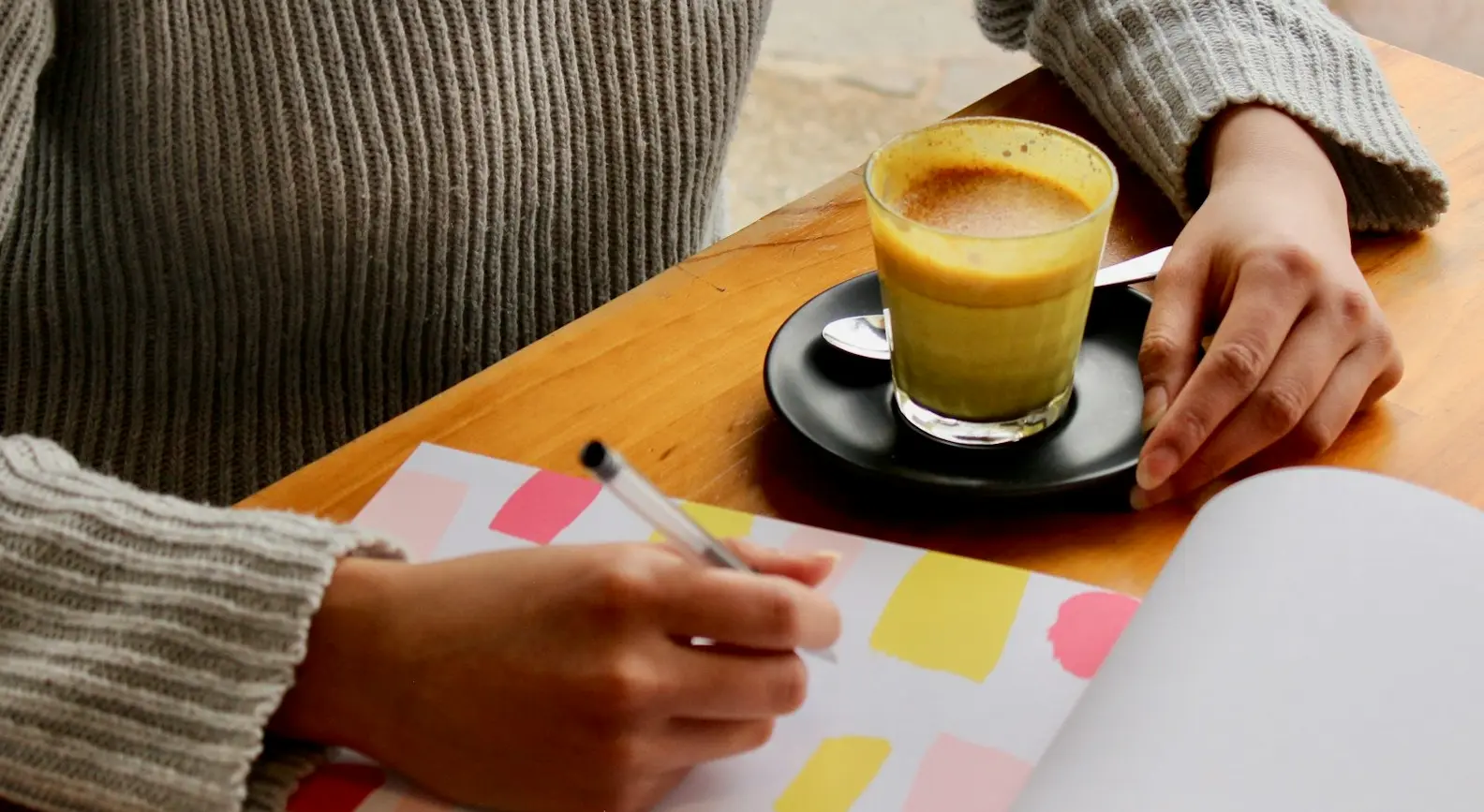 person holding pen with coffee on table
